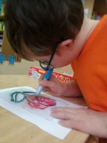 na zdjęciu chłopiec malujący pracę plastyczną